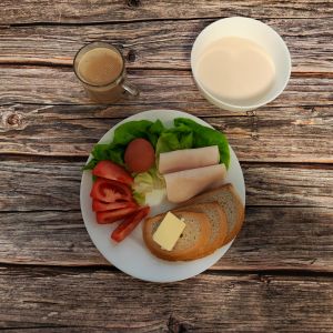 Zdjęcie przedstawia Dietę łatwostrawną: Płatki jęczmienna na mleku Bułka pszenna długa krojona Masło extra Jajko gotowane Kawa zbożowa z mlekiem Pomidor Filet zapiekany drobiowy Sałata zielona